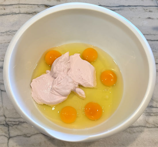 In a large bowl, whisk together the eggs, strawberry yogurt, and plain yogurt until smooth.