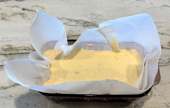 Pour the batter into the prepared loaf pan and spread evenly.