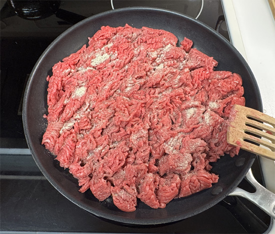 Add the ground beef. Break it up with a spatula and sprinkle in the seasoning mix.