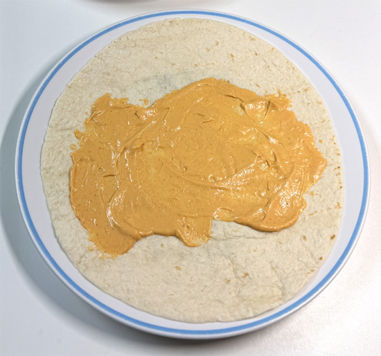 Spread 2 Tbsp chipotle aioli sauce down the center of each tortilla.
