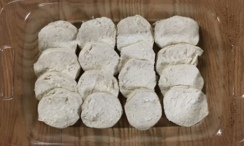 Biscuits cut in half and placed in a pan. 