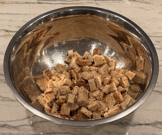 Cut bread into 1/2-inch squares and place in a large mixing bowl. 