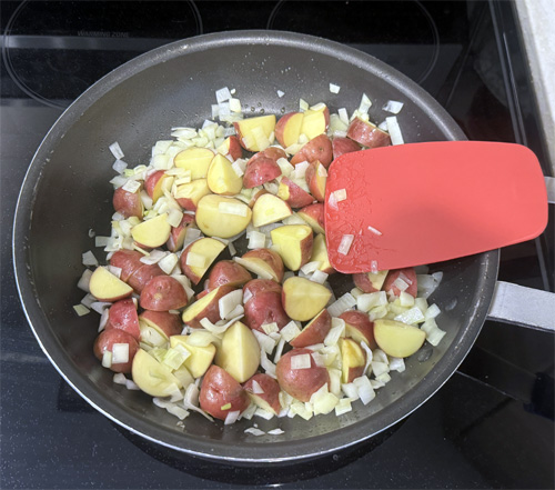 Heat a large skillet over medium heat. Add the olive oil, potatoes and onion. Cook for about 5-7 minutes, stirring frequently until the onion turns translucent.