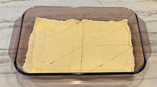 Unroll one tube of crescent rolls and press into the bottom of the prepared casserole dish. Bake for 7 minutes, then remove and set aside.