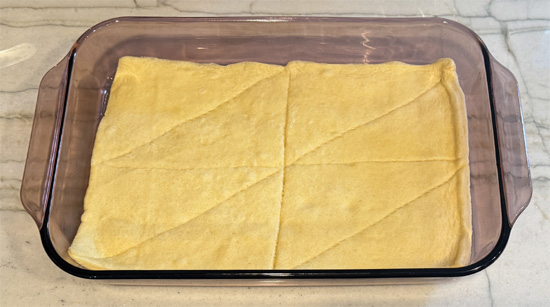 Unroll one tube of crescent rolls and press into the bottom of the prepared casserole dish. Bake for 7 minutes, then remove and set aside.
