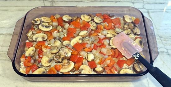 Layer the casserole: spread cheese-sausage mixture over the baked crust, add vegetables as the next layer, then top with scrambled eggs.