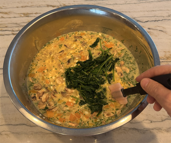 Stir the cooked spinach and vegetables into the egg mixture.