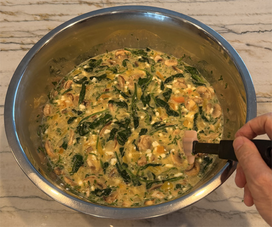 Stir the cooked spinach and vegetables into the egg mixture.