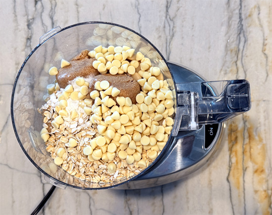 In a blender or food processor, combine the butter beans, Swerve Brown sugar, eggs, vanilla, oats, baking powder, baking soda, salt and 1/2 cup of the white chocolate chips. Blend until smooth, about 2 to 3 minutes, scraping down the sides once. 