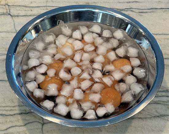 Prepare a large bowl with ice and water to create an ice bath. Transfer the eggs from the hot water to the ice bath. Let the eggs sit in the ice bath for at least 10 minutes. This stops the cooking process and makes the eggs easier to peel.