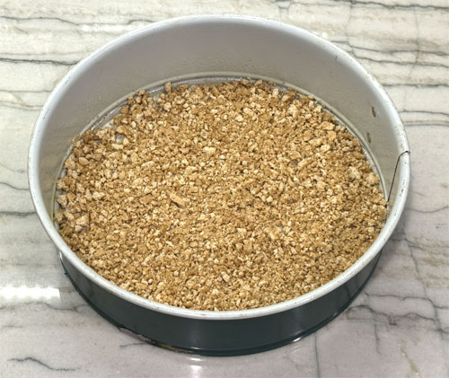 Pour the graham cracker and butter mixture into the bottom of a springform pan and flatten it out; this will be your crust.