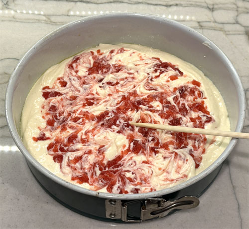Use a chopstick to push the jelly into the cheesecake and swirl it around a little.