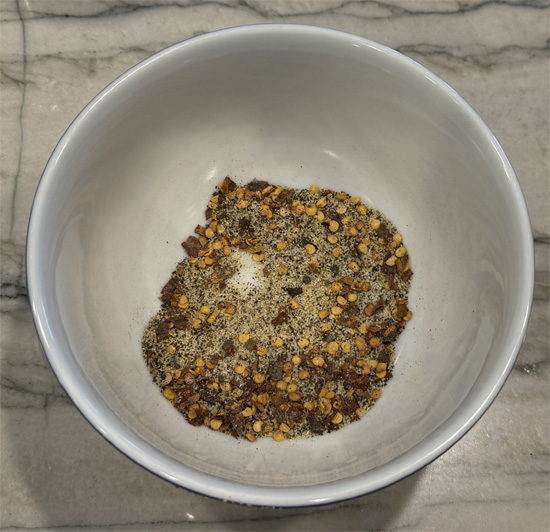 Stir into the cooked ground beef 1 teaspoon garlic powder, 1/2 teaspoon salt, 1/2 teaspoon pepper, and 1 teaspoon crushed red pepper. Remove from the heat and set aside.