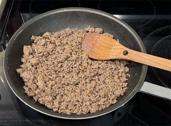 Stir into the cooked ground beef 1 teaspoon garlic powder, 1/2 teaspoon salt, 1/2 teaspoon pepper, and 1 teaspoon crushed red pepper. Remove from the heat and set aside.