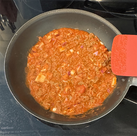 Put the pasta sauce, frozen beef crumbles and chopped onion in a pan over medium heat. Stir and cook for five minutes, until it's heated up. 