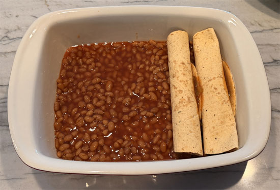 Lay out the tortillas and spread 2 Tbsp. of the enchilada mixture on each one. Wrap each tortilla around a hot dog and place it seam side down in the baking dish, on top of the beans.