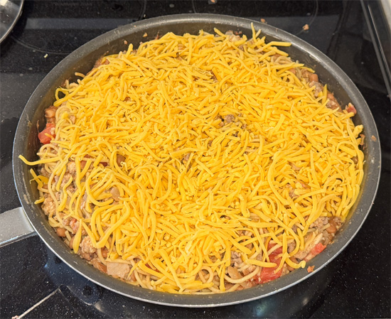 Sprinkle the shredded reduced-fat cheddar cheese AND the green onions over the pasta. Then, cover the skillet to allow the things to melt together for about 3-5 minutes.
