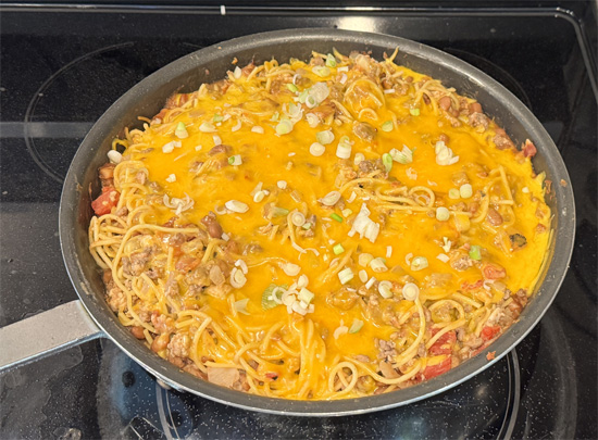 Sprinkle the shredded reduced-fat cheddar cheese AND the green onions over the pasta. Then, cover the skillet to allow the things to melt together for about 3-5 minutes.