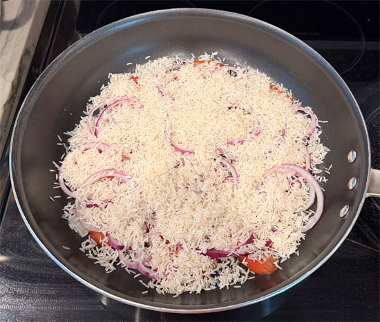 Spread the washed and drained rice evenly over the vegetables. 