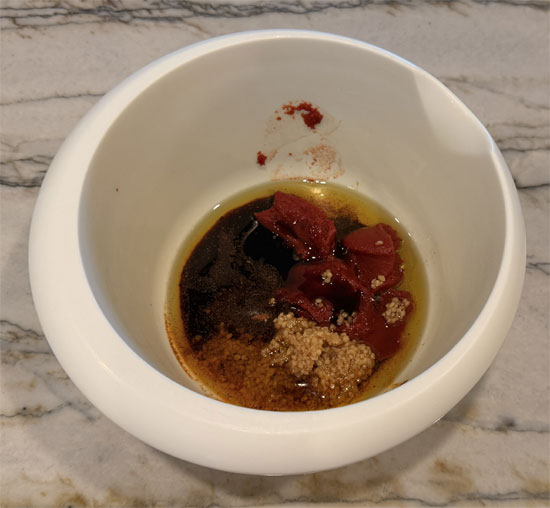 In a medium bowl, mix together salt, pepper, Baharat spice, paprika, olive oil, tomato paste, date syrup, and garlic. 