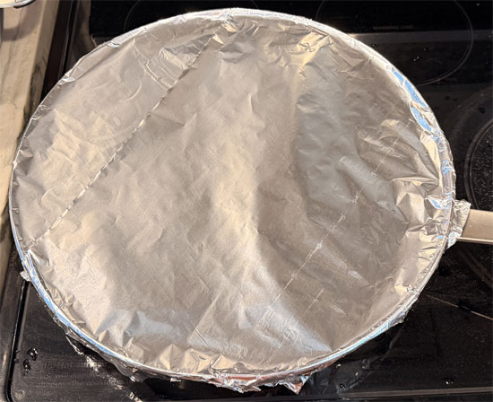 Wet a piece of parchment paper and place it over the chicken. Cover the pan with aluminum foil. 