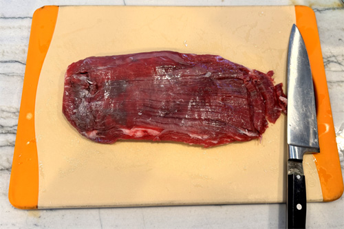 Cut the steak into very thin strips. Cut against the grain at about a 10-degree angle. Set aside.