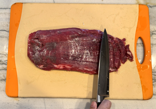 Cut the steak into very thin strips. Cut against the grain at about a 10-degree angle. Set aside.