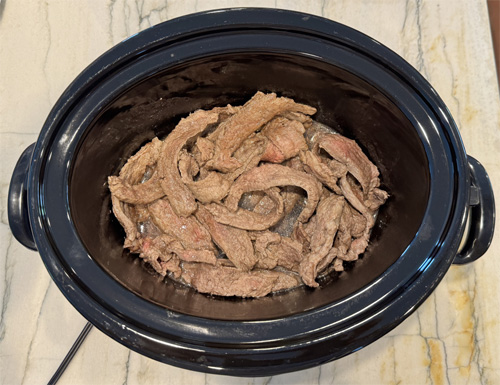 Heat the olive oil in a large skillet over medium-high heat. Working in batches, add the steak strips in a single layer. Cook about 1–2 minutes per side, just until browned. Transfer the browned steak to your slow cooker.