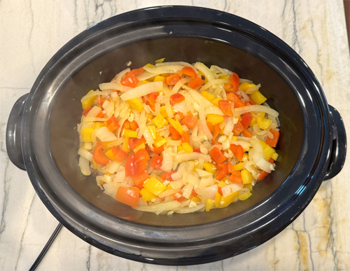 Use the same skillet and saute the bell peppers and onion. Cook for about 3-4 minutes until they soften, then add the minced garlic and cook for another 30 seconds. Pour all the ingredients into the slow cooker on top of the steak. 