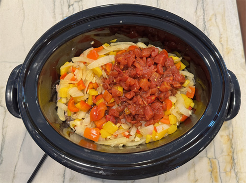 In a medium bowl, stir together the diced tomatoes (with juice), soy sauce, beef broth, brown sugar, Worcestershire sauce, ginger, black pepper, and crushed red pepper flakes (if using). Pour this mixture over the steak and veggies in the slow cooker. Stir gently to ensure everything is evenly coated.