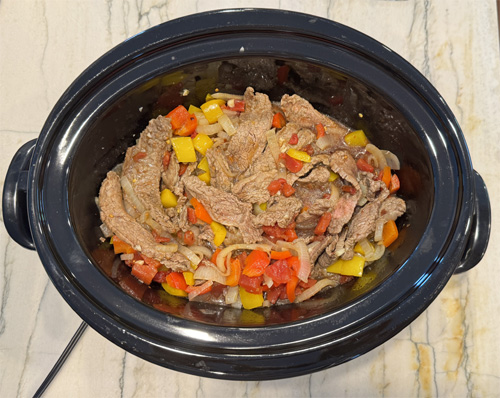 In a medium bowl, stir together the diced tomatoes (with juice), soy sauce, beef broth, brown sugar, Worcestershire sauce, ginger, black pepper, and crushed red pepper flakes (if using). Pour this mixture over the steak and veggies in the slow cooker. Stir gently to ensure everything is evenly coated.