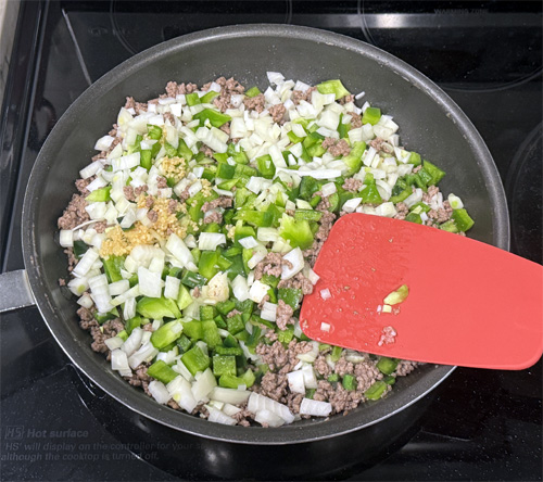 Add the onion, bell pepper, poblano pepper and garlic to the beef and continue cooking, stirring occasionally for another 3 minutes.