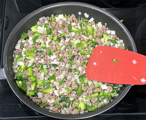 Add the onion, bell pepper, poblano pepper and garlic to the beef and continue cooking, stirring occasionally for another 3 minutes.
