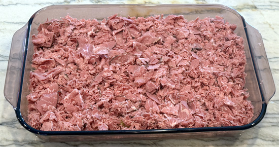 Layer the drained sauerkraut over the bread, then spread the chopped pastrami, followed by the sour cream mixture, then the mozzarella and finally the Swiss cheese over top. 