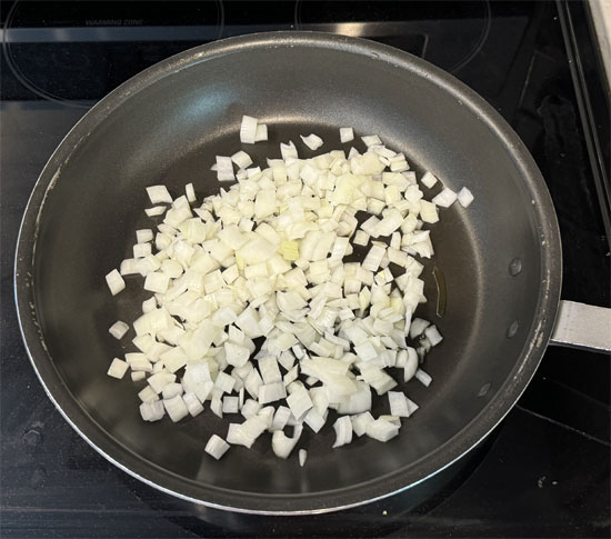 Chop up 1 1/2 cups of onion while heating a large skillet (the one you cooked the chicken in) over medium heat. Once the pan is hot, lightly spray it with olive oil.
