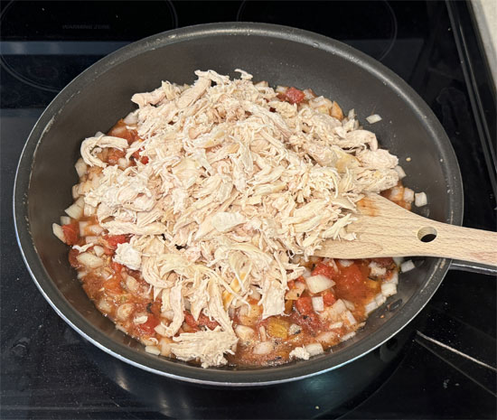 Stir in the shredded chicken, can of drained corn, salt and pepper to the onion and tomatoes that are cooking. Mix it all together and cook for another 3 minutes until heated through and combined.