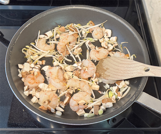 Heat a large skillet over medium heat. Add 1 tablespoon of olive oil to the pan. Saute the shrimp, mushrooms, sprouts, and green onions until the shrimp turns pink and the vegetables are crisp-tender for about 2 minutes. Then remove from the heat.