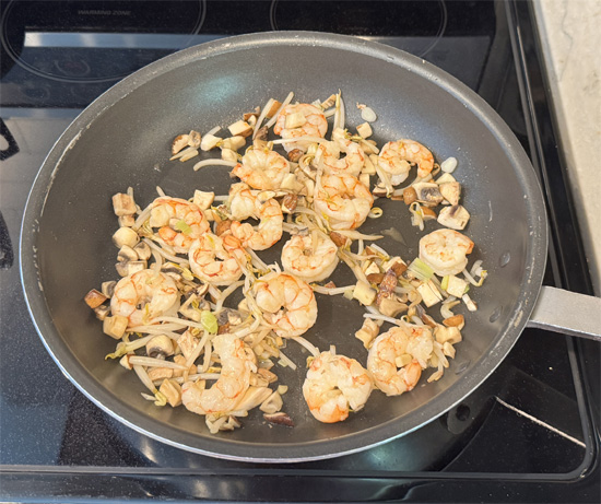 Heat a large skillet over medium heat. Add 1 tablespoon of olive oil to the pan. Saute the shrimp, mushrooms, sprouts, and green onions until the shrimp turns pink and the vegetables are crisp-tender for about 2 minutes. Then remove from the heat.