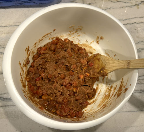 In a large bowl, mix together the refried beans, diced tomatoes, chili powder, ground cumin, and crushed red pepper flakes (if using). 