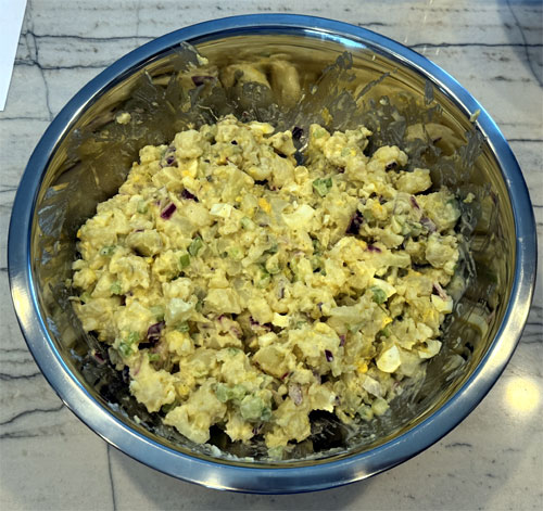 Add the cooled potatoes, cauliflower, and chopped eggs into the dressing. Gently fold everything together until all ingredients are well-coated, taking care not to break up the cauliflower florets too much.