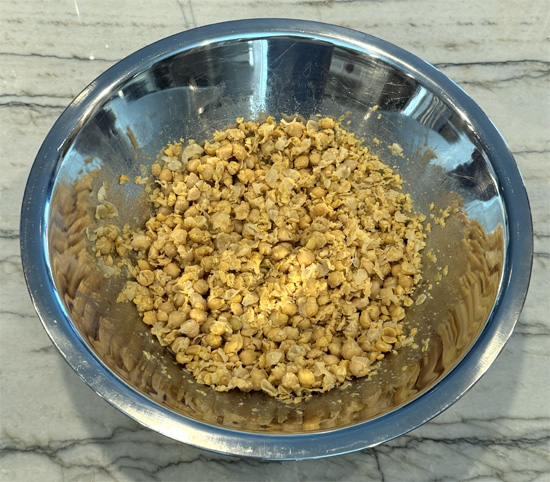Drain the chickpeas and put them in a mixing bowl. Then, mash them up.