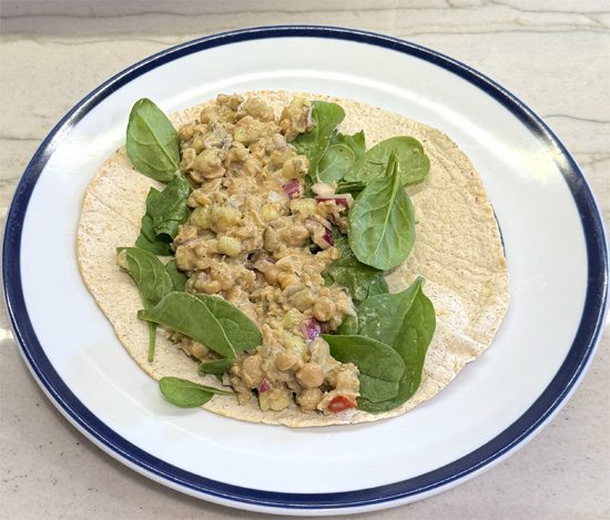 Lay out a tortilla wrap, toasted, if you want. Put a cup of baby spinach and half a cup of the chickpea mix on the tortilla and roll it up. 