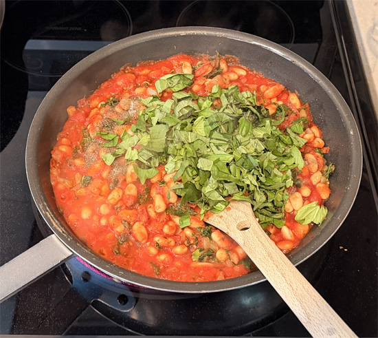 Stir in the basil, salt and pepper. Reduce heat to low and simmer gently for 5 minutes.