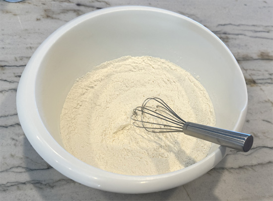Mix dry ingredients. In a large bowl, whisk together flour, baking powder, and protein powder. Make sure to sift the baking powder first to avoid lumps.