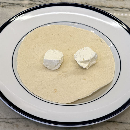 Lay the tortilla wrap flat and spread the reduced-fat cream cheese evenly on top.