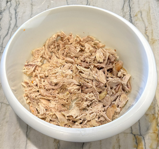 Prepare the chicken breast or remove it from a rotisserie chicken made at the grocery store. Put it in the slow cooker.