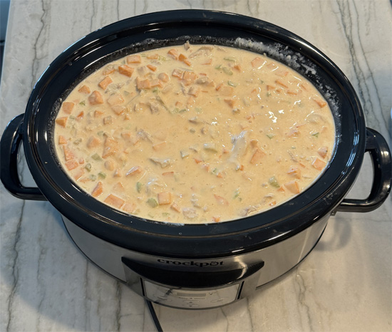 Add all the remaining ingredients, EXCEPT the blue cheese. Pour in the three cans of soup, the sour cream, buffalo wing sauce, carrots, celery and sweet potatoes. Stir together.