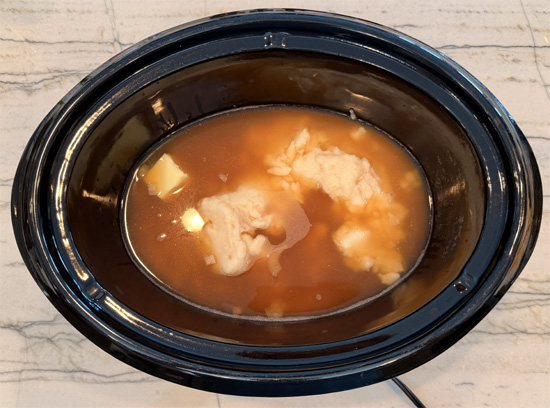 Place the chicken, condensed soup, onion and butter in a large slow cooker. Add the bone broth to cover and stir well. 