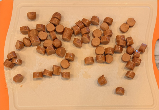 While the water heats, warm a frying pan over medium heat and coat it lightly with olive oil spray. Add the hot dogs and cook 6 to 7 minutes, turning frequently, until every side is lightly browned. Cut them into bite sized pieces and set aside.