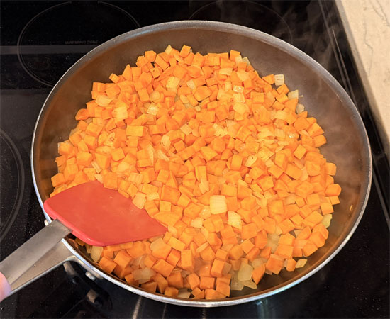 Heat a large pot or pan over medium heat. Add olive oil, sweet potatoes, and onion. Cook, stirring occasionally, until onions become tender, about 8 to 10 minutes.